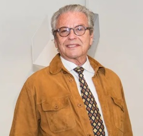 Picture of a white man with glasses wearing a brown jacket and print tie.  This is the artist, Rafael Barrios. 